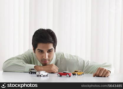 Thoughtful young male executive looking at model cars
