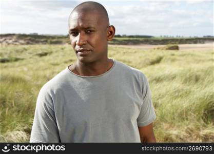 Thoughtful Young Man Standing On Beach Amongst Dunes