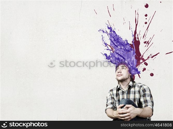 Thoughtful young man with colorful splashes out of his head. Man with colored head