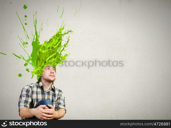 Thoughtful young man with colorful splashes out of his head. Man with colored head