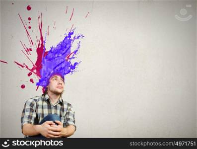 Thoughtful young man with colorful splashes out of his head. Man with colored head