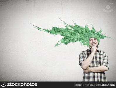 Thoughtful young man with colorful splashes out of his head. Man with colored head