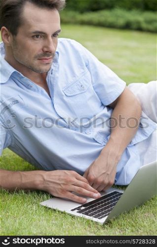 Thoughtful young man with laptop in park