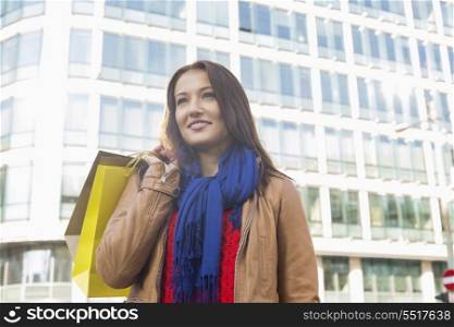 Thoughtful young woman carrying shopping bags in winter