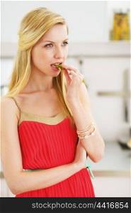 Thoughtful young woman having snack in kitchen