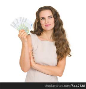 Thoughtful young woman holding fun of euro banknotes