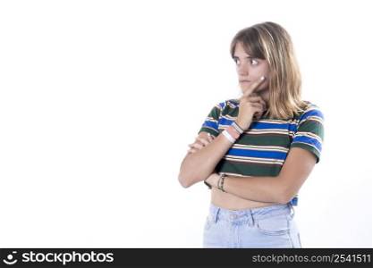 Thoughtful young woman holding one arm under her chin, on white background. Serious girl looking to the left with copy space on background.
