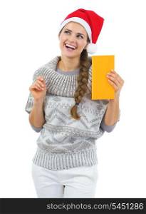 Thoughtful young woman in sweater and christmas hat holding letter