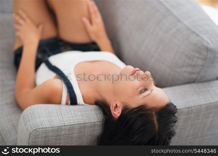 Thoughtful young woman laying on couch