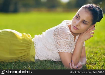 Thoughtful young woman laying on grass