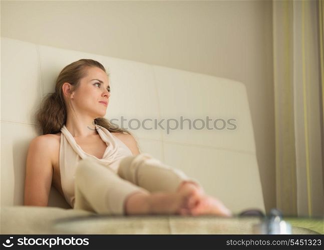 Thoughtful young woman laying on sofa