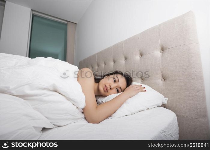 Thoughtful young woman lying in bed