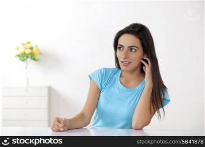 Thoughtful young woman sitting at table in house
