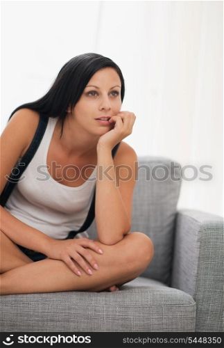 Thoughtful young woman sitting on couch