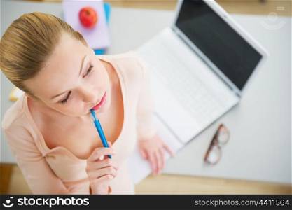 Thoughtful young woman studying in kitchen