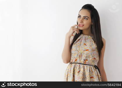 Thoughtful young woman wearing sundress looking at copy space on white background