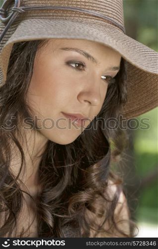 Thoughtful young woman wearing sunhat in park
