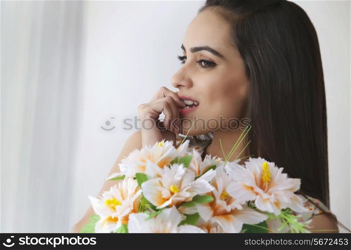 Thoughtful young woman with bunch of flowers