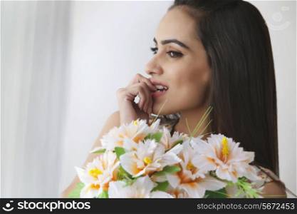 Thoughtful young woman with bunch of flowers