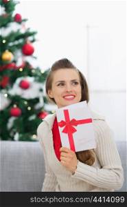 Thoughtful young woman with Christmas postcard