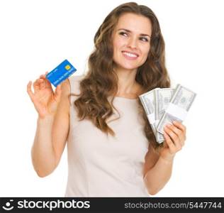 Thoughtful young woman with credit card and dollars looking on copy space