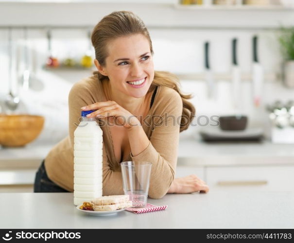 Thoughtful young woman with crisp bread and milk in modern kitchen