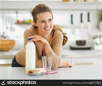 Thoughtful young woman with crisp bread and milk in modern kitchen