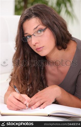 Thoughtful young woman writing in a book