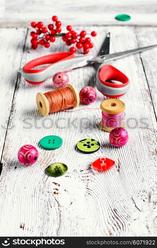 Thread,buttons,beads and scissors on the table light vintage