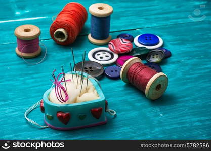 thread buttons for crafts on turquoise wooden background. working tool dressmaker