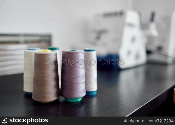 Thread coils on the table in atelier, nobody. Dressmaking occupation and professional sewing, handmade tailoring business, handicraft hobby, workshop interior on background. Thread coils on the table in atelier, nobody