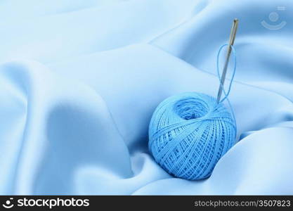 thread on blue silk background close up