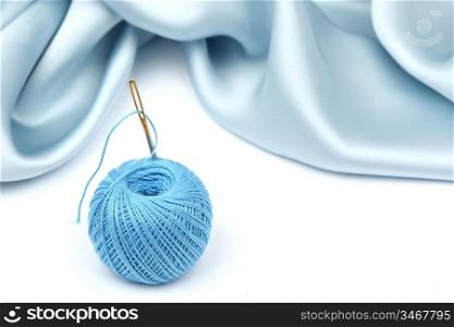 thread on blue silk isolated close up