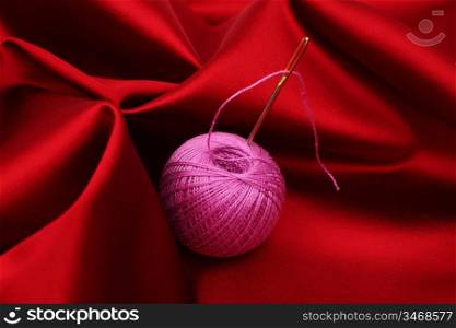thread on red silk background close up