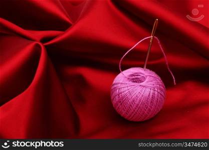 thread on red silk background close up