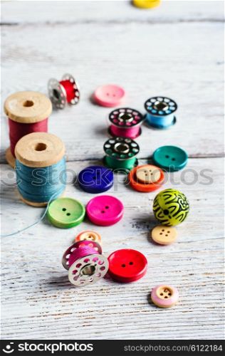 Threads and a set of buttons and bobbin on a bright light background. Working inventory seamstresses
