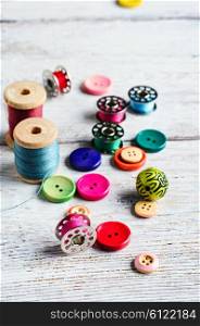 Threads and a set of buttons and bobbin on a bright light background. Working inventory seamstresses