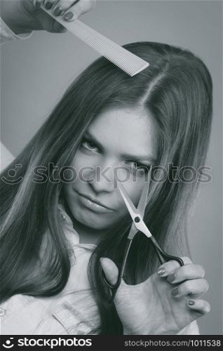 Threat danger crime beauty care haircut coiffure concept. Suspicious barber with tools. Dangerous weird looking hairdresser lady holding sharp scissors and comb.. Suspicious barber with tools.