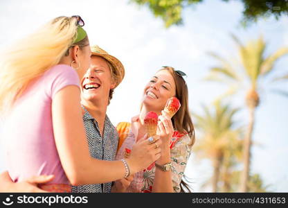 Three adult friends laughing and eating ice cream cones, Majorca, Spain