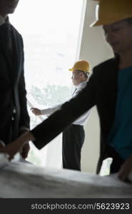 Three architects in hardhats examining blueprints in an office building