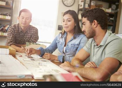 Three Architects Sitting Around Table Having Meeting