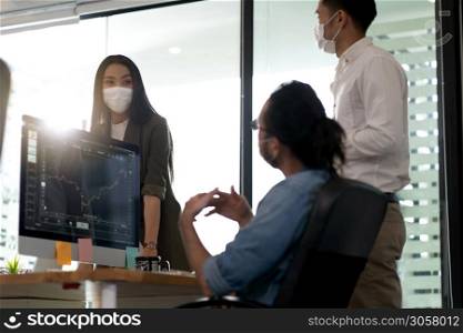 Three asian business person discuss their work in morning after office reopen due to coronavirus COVID-19 pandemic. They wear protective face mask to prevent infection. New normal office life concept.