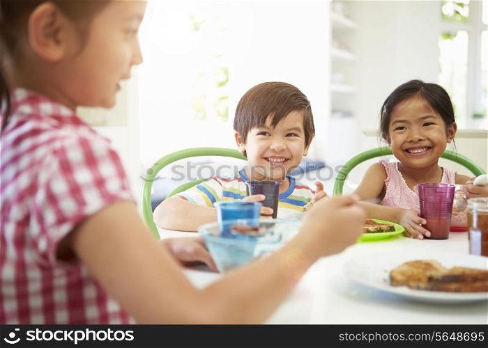 Three Asian Children Having Breakfast Together In Kitchen