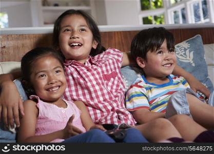 Three Asian Children Sitting On Sofa Watching TV Together