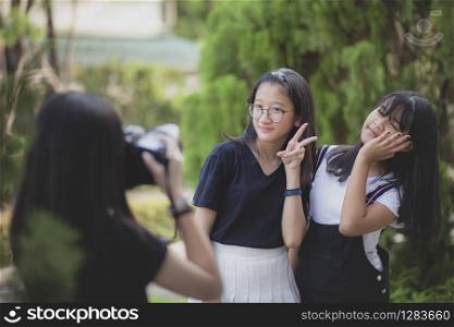 three asian teenager with dslr camera in hand pose as fashion model