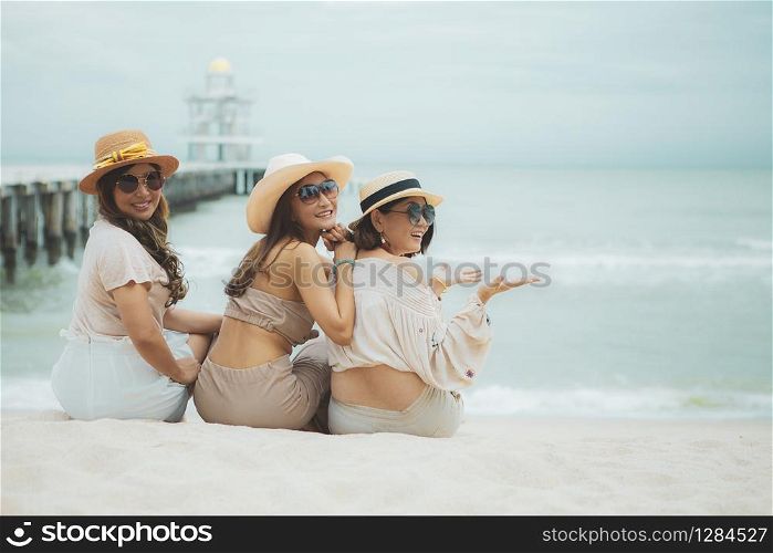three asian woman sitting on vacation sea beach with happinessw emotion