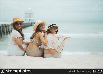 three asian woman sitting on vacation sea beach with happinessw emotion