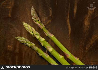 Three asparagus over dark brown wooden