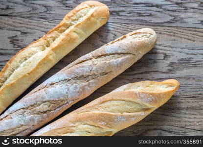 Three baguettes on the wooden background