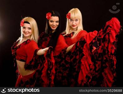 Three beautiful girls in Gipsy suits on a black background